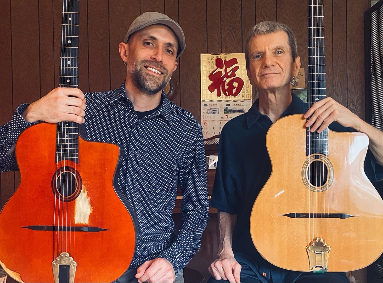 Two men posing for a photo with two guitars.